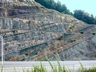 Kentucky side of the Pound Gap Road Cut on Route 23, this exposure is of the Mississippian black Sunbury Shale overlain by the olive-gray to red Grainger Formation which takes up most of the image and is composed of alternating relatively continuous to occasionally channeled beds of sand with uniform sharp bedding planes and shale; both lithologies vary in thickness and the sands often exhibit Bouma sequences suggesting deposition from turbidite currents that were active over a mid to outer fan setting. At the top of the outcrop is the base of the Mississippian Newman Limestone