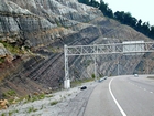 The erosive contact between the Mississippian Grainger Formation and the base of the overlying Newman Limestone. The Grainger fills most of the photograph and is composed of alternating relatively continuous to occasionally channeled beds of sand with uniform sharp bedding planes and shale; both lithologies vary in thickness and the sands often exhibit Bouma sequences suggesting deposition from turbidite currents that were active over a mid to outer fan setting. At the base of the outcrop is Mississippian black Sunbury Shale