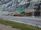 The base of the visible road cut is marked by the erosive contact between the Mississippian Grainger Formation and the base of the overlying Newman Limestone. The Mississippian Newman Limestone fills most of the image and is composed of relatively continuous beds of carbonate that locally develope mounding and channeling. Beds have irregular but sharp bedding planes and some shale partings and siltstones. At the base of the outcrop is Mississippian Grainger Formation