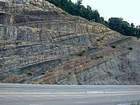 Pound Gap where the base of the visible portion this road cut marks the top the Lower Mississippian Sunbury Shale that is locally coffee colored. Most of the photograph is of the Mississippian Grainger Formation which is composed of alternating relatively continuous to occasionally shallowly channeled beds of sand with uniform sharp bedding planes and shale; both lithologies vary in thickness and the sands often exhibit Bouma sequences suggesting deposition from turbidite currents that were active over a mid to outer fan setting. The lower portion of the formation is shale rich and probably from a deeper water setting and a more distal portion of the fan. The top of the photograph is marked by the overlying Lower Mississippian Newman Limestone Formation