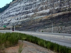 Pound Gap where at the base of the visible portion this road cut is the top the Lower Mississippian Sunbury Shale. Most of the photograph is of the Mississippian Grainger Formation, here composed of alternating relatively continuous to occasionally shallowly channeled beds of sand with uniform sharp bedding planes and shale; both lithologies vary in thickness and the sands often exhibit Bouma sequences suggesting deposition from turbidite currents that were active over a mid to outer fan setting. The lower portion of the formation is shale rich and probably from a deeper water setting and a more distal portion of the fan. The top of the photograph is marked by the overlying Lower Mississippian Newman Limestone Formation