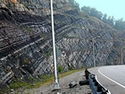 Pound Gap where the base of the visible portion this road cut is the top the Lower Mississippian Sunbury Shale. Most of the photograph is of the Mississippian Grainger Formation, here composed of alternating relatively continuous to occasionally shallowly channeled beds of sand with uniform sharp bedding planes and shale; both lithologies vary in thickness and the sands often exhibit Bouma sequences suggesting deposition from turbidite currents that were active over a mid to outer fan setting. The lower portion of the formation is shale rich and probably from a deeper water setting and a more distal portion of the fan. The top of the photograph is marked by the overlying Lower Mississippian Newman Limestone Formation