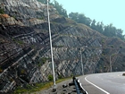 Pound Gap where most of the photograph is of the Mississippian Grainger Formation, which here is composed of alternating relatively continuous to occasionally shallowly channeled beds of sand with uniform sharp bedding planes and shale; both lithologies vary in thickness and the sands often exhibit Bouma sequences suggesting deposition from turbidite currents that were active over a mid to outer fan setting. The lower portion of the formation is shale rich and probably from a deeper water setting and a more distal portion of the fan. The top of the photograph is marked by the overlying Lower Mississippian Newman Limestone Formation