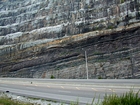 A the base of the photograph is the Mississippian Grainger Formation which is composed of alternating relatively continuous of sand with uniform sharp bedding planes and shale. Most the upper two thirds of the photograph is the overlying Lower Mississippian Newman Limestone Formation. This is composed of relatively continuous beds of shallow water carbonate that locally develop mounds and are channeled. Beds have irregular but sharp bedding planes with some shale partings and prominent dolomitic siltstones