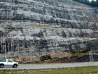 A the base of the photograph is a small exposure of the Mississippian Grainger Formation with continuous beds of sand with uniform sharp bedding planes and shale. Most the upper portion of the photograph is the Lower Mississippian Newman Limestone Formation. This is composed of relatively continuous beds of shallow water carbonate that locally develop mounds and are channeled. Beds have irregular but sharp bedding planes with some shale partings and dolomitic siltstones