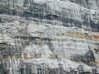 Bottom tan layer marks top of unit 111 and base of unit 110, see the measured Geological Section, Kentucky Geological Survey Field Trip Guide 1998. It is interpreted that storm waves eroded this shelf and caused the shallow water limestones of the Lower Mississippian Newman Limestone Formation to develop their irregular character while local currents formed the low angle cross beds and carbonate mound margins with clinoforms formed as these migrated across this setting. Note the prominent dolomitized silt-forming core of enveloping carbonate mound in the center of this image. The silts are probably have a subaerial source