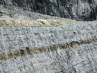 During deposition storm waves are believed to have eroded the shelf surface and caused these shallow water limestones of the Lower Mississippian Newman Limestone Formation to have their irregular character, while local currents accounted for the development of low angle cross beds and mound margin clinoforms suggesting migrating carbonate bodies moving across this setting. Note two prominent beds of dolomitized silt interbedded with the shallow carbonates in the center of this image. These silts probably have a subaerial source. Lower tan/dark layer is top 110 and base of 109, see the measured Geological Section, Kentucky Geological Survey Field Trip Guide 1998. 