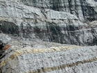 During sediment deposition storm waves are interpreted to have eroded the shelf surface and caused these shallow water limestones of the Lower Mississippian Newman Limestone Formation to have their irregular character, while local currents accounted for the development of low angle cross beds and mound margin clinoforms suggesting migrating carbonate bodies moving across this setting. Note two prominent beds of dolomitized silt interbedded with the shallow carbonates in the center of this image. These silts probably had a subaerial source. Lower tan/dark layer is top unit of unit 110 and base of 109, see the measured Geological Section, Kentucky Geological Survey Field Trip Guide 1998