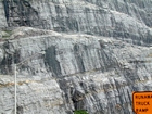 Storm waves are interpreted to have eroded this shelf surface and caused the shallow water limestones of the Lower Mississippian Newman Limestone Formation to have their irregular character, while local currents account for the development of low angle cross beds and mound margin clinoforms suggesting migrating carbonate bodies moving across this setting. Note two prominent beds of dolomitized silt interbedded with the shallow carbonates in the center of this image. These are interpreted to be the product of subaerial exposure and windblown transport to their current, probably marine depositional setting. The large black area centered around the angled arm of the light standard is unit 109, beneath is 110 and so on down, see the measured Geological Section, Kentucky Geological Survey Field Trip Guide, 1998