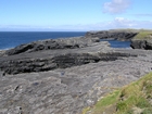 Cliffs and eroded bedding planes of the coastal monocline of Namurian deepwater sediments of the Ross Formation. Fisherman's Point ledge is situated in the middle background to the north. In foreground are bedded and slumped sediments of the Ross Formation.