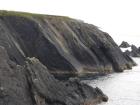 Beds of channelled sands and silty muds of Gull Island Formation whose bedding plane partings have a variety of features on their surfaces including ripples and goniatite fossils.