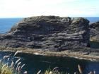 Island cliff of Gull Island Formation exhibiting mixed channel sands and lobes and large deformational structures interpreted to have been transported downslope from a deltaic source above. Note margin of large slump filled channel cut into rhythmic slope deposits of silt and mud.