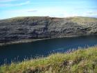 Cliff of Gull Island Formation composed of mixed channel sands and lobes and large deformational structures interpreted to have been transported downslope from a deltaic source above. To right edge note margin of large slump filled channel cut into rhythmic slope deposits of silt and mud.