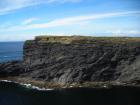 Cliff at Tullig Point with mix of Tullig and Gull Island Formations. Note delta front silts and muds above, while below are Gull Island Formation mixed channel sands and lobes and large deformational structures interpreted to have been transported downslope from a deltaic source above. Note large slump filled gauges cut into rhythmic slope deposits of silt and mud.