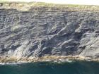 Cliff at Tullig Point with mix of Tullig and Gull Island Formations. Note delta front silts and muds above, while below are Gull Island Formation mixed channel sands and lobes and large deformational structures interpreted to have been transported downslope from a deltaic source above. Note large slump filled gauges cut into rhythmic slope deposits of silt and mud.