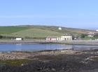 West end of Kilbaha Bay with Keatings Bar and Kilbaha Village in the background and in the forground the wave cut pavement of the intertidal zone.