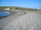 Pebble Beach at West end of Kilbaha Bay with Keatings Bar and Kilbaha Village in the background.