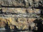 Scouring and soft sediment deformation at the base of the channeled sand lobes of the Ross Formation on the West side of Kilbaha Bay. Note thin interbedded shales and sands between the channeled lobe sands.