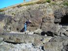 Amalgamated channeled sand of the Ross Formation of West Kilbaha Bay. Below is a further bedded channel sand. Note rounded beach cobbles generated by the Atlantic storm surges that beat against these low cliffs. Above is Pleistocene glacial drift at top section filling the eroded Pleistocene surface on the Carboniferous.