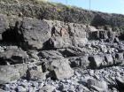 Amalgamated channeled sand of the Ross Formation of West Kilbaha Bay. Below is a further bedded channel sand. Note rounded beach cobbles generated by the Atlantic storm surges that beat against these low cliffs. Above is Pleistocene glacial drift at top section filling the eroded Pleistocene surface on the Carboniferous.