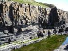 At base of small cliff to the right is the margin of megaflute in the Ross Formation on the West side of Kilbaha Bay. Above are the amalgamated sands of a deepwater channeled sand lobe.