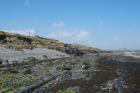 Deepwater channeled sands of the Ross Formation interbedded with shale above the wave-cut platform in the east of Kilbaha Bay. Note storm surge beach gravels heaped against cliff and the Pleistocene glacial drift gravels at top of section.