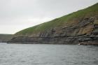 West end of Rehy Cliffs just east of a monocline. At level of sea and above are mixed thin bedded inter channel sands. Above is an amalgamated channel fill with feather edge of channel wings. Downlapping onto this channel sand are clinoforms interpreted to be filling the eroded interior of a channel.