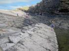 Amphitheatre in cliff tops on south side of Trusklieve wave eroded cliff margined slot exposes Tullig Formation Upper Carboniferous or Namurian age delta front. Lower portion of amphitheatre cliffs are rhythmic alternations of silt, sand and mud that accumulated just above wave base. Top of cliff formed by channelled quartzose sands sorted by waves that impinged on the delta front and filled distributary channels and/or proximal bar sands (Andy Pulham personal communication and Martinsen et al., 2008).