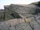 Crest of cliff is exposure of Tullig Formation rhymically bedded silts and muds at and below wave base of Upper Carboniferous or Namurian age. Below are channelled and sorting of the quartz rich sands from the delta front, reflectingeffect of waves impinging on the delta front sands that filled distributary channels and/or proximal bar sands (Andy Pulham personal communication and Martinsen et al., 2008).