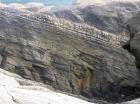 Top of cliff are cross bedded sands of Tullig Formation of Upper Carboniferous or Namurian age. These are wave and current sorted delta front sands filling distributary channels and/or proximal bar sands. Below are deeper water within wave base rhythmically bedded silts and muds (Andy Pulham personal communication and Martinsen et al., 2008).