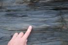 Alternations of silt, sand and mud with climbing ripples that accumulated just above wave base. Base of cliffed amphitheatre on south side of Trusklieve wave eroded cliff margin (Andy Pulham personal communication and Martinsen et al., 2008). Section part of Tullig Formation Upper Carboniferous or Namurian age delta front.